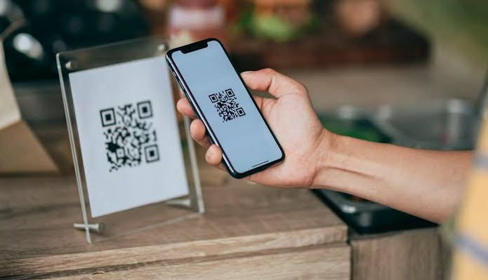 Golpe do QR Code — celular escaneando QR Code falso colado sobre o código original em estabelecimento